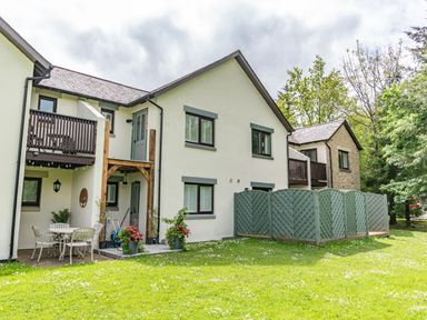 A white two-story house with balconies and a green lawn in front at Whisk Away Cottage Greystoke near Troutbeck Near Penrith