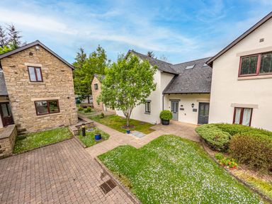 A courtyard with stone and white houses grass trees and shrubs at Whisk Away Cottage in Greystoke near Troutbeck Near Penrith