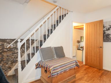 A staircase with a carpet runner next to a wooden chest with cushions and a striped blanket at 5 Thomas Street in Llanberis