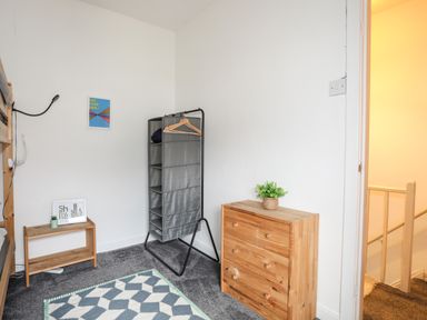 A bedroom with a wooden chest of drawers a small wooden table and a hanging fabric wardrobe at 5 Thomas Street in Llanberis