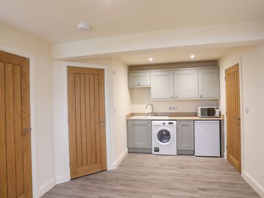 A kitchenette with washing machine fridge microwave wooden doors and cupboards at Pennant Igyn in Mynytho near Abersoch