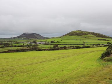 Green fields with two hills under a cloudy sky in a rural area at Pennant Igyn in Mynytho near Abersoch