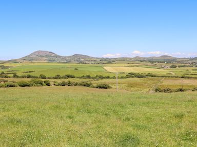 A landscape of green fields with hills in the background at Pennant Igyn Mynytho near Abersoch