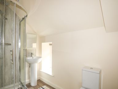 A bathroom with a shower enclosure a pedestal sink a mirror a window and a toilet at Pennant Igyn in Mynytho near Abersoch