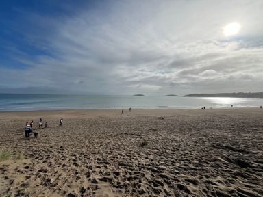 A sandy beach with people walking and the ocean in the background at Pennant Igyn in Mynytho near Abersoch