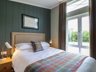 A bedroom with a double bed a framed picture bedside tables with lamps and a window with curtains at Holly Lodge in Winthorpe near Newark-On-Trent