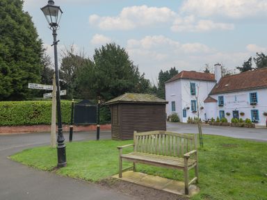 A wooden bench on grass near a street lamp and a small wooden shed by a building named The Lord Nelson at Winthorpe near Newark-On-Trent