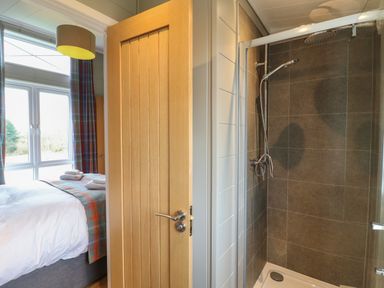 A bathroom with a shower and a view into a bedroom with a bed and window at Cedar Lodge in Newark-On-Trent