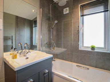 A bathroom with a sink cabinet mirror bathtub shower and a window with blinds at Cedar Lodge in Newark-On-Trent