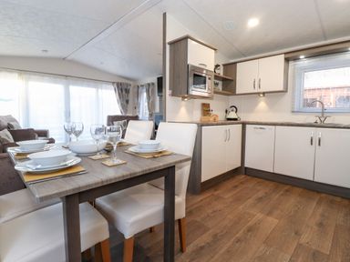 A kitchen and dining area with a table set for four and sofas in the background at Orion in Felmoor Park