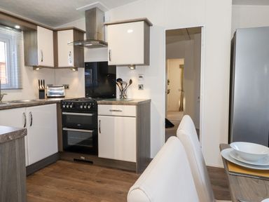 A kitchen with white cabinets black stove utensils a toaster and dining chairs at Orion in Felmoor Park