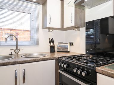 A kitchen countertop with a toaster a knife block a dual sink and a gas stove at Orion in Felmoor Park