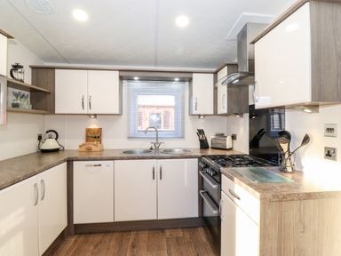 A kitchen with countertops cabinets a stove double sink utensils and a window at Orion in Felmoor Park