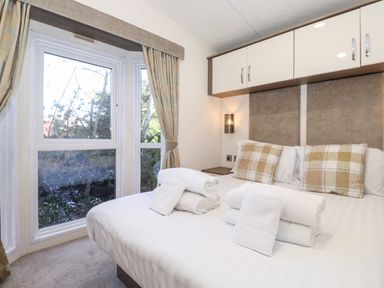 A bedroom with a double bed white linens folded towels pillows and a window with curtains at Orion Felmoor Park