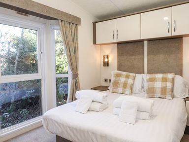 A bedroom with a double bed pillows and folded towels by a window at Orion in Felmoor Park