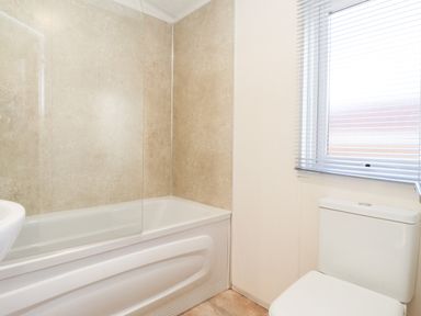 A bathroom with a bathtub and a toilet next to a window with blinds at Orion in Felmoor Park