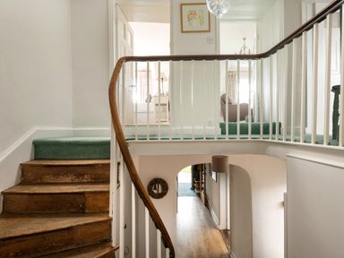 A staircase with wooden steps and green carpet leading to a hallway with white walls and railing at Tros Yr Afon in Beaumaris