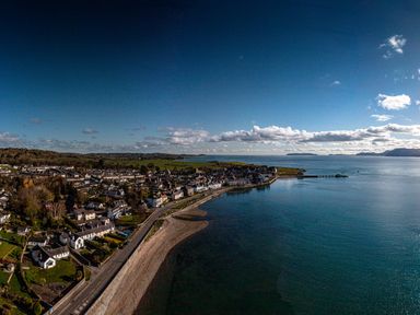 A coastal town with houses along the shoreline and a pier extending into the sea at Tros Yr Afon in Beaumaris