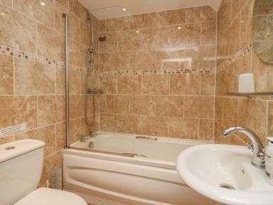 A bathroom with a bathtub shower combination toilet and sink at Storrs Lodge in Bowness-On-Windermere