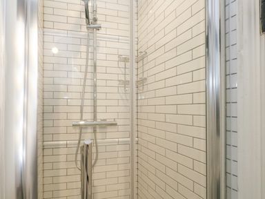 A shower enclosure with white subway tiles and a chrome showerhead at Lime Cottage in Burton Bradstock
