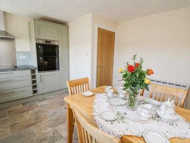 A dining table with floral centerpiece and china tea set in a kitchen at 2 Sunny Hill in Porthgain near St Davids
