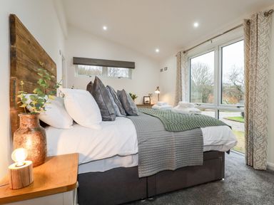 A bedroom with a large bed made with pillows and folded towels next to a window with curtains at 7 Valley View in Lanreath