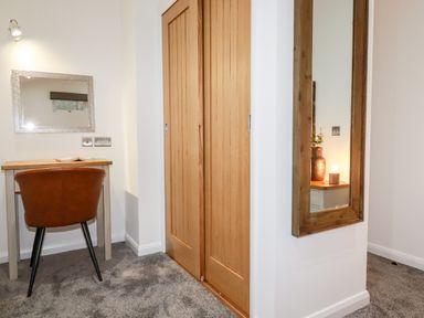 A small desk with a brown chair under a wall mirror next to wooden closet doors and a large wall mirror in a corner at 7 Valley View Lanreath