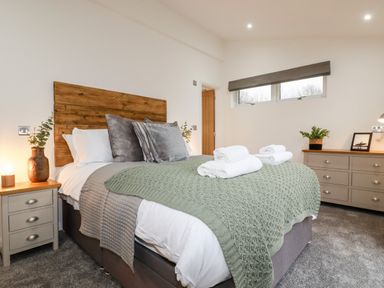A bedroom with a bed with towels on it bedside tables and a dresser at 7 Valley View in Lanreath