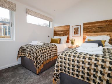 A bedroom with two single beds with wooden headboards and patterned blankets at 7 Valley View in Lanreath