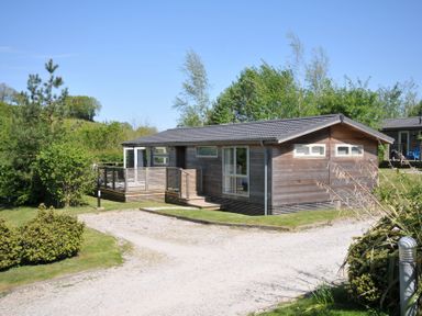 A wooden house with a deck and garden space at 7 Valley View in Lanreath