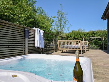 An outdoor terrace with a hot tub and seating at 7 Valley View in Lanreath