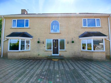 The front exterior of a two-story brick house with a dark front door and symmetrical windows at Sanderson House in Cleator Moor