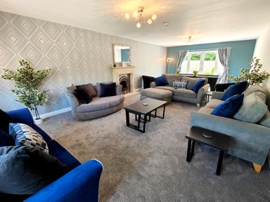 A living room with multiple sofas a coffee table plants and a fireplace at Sanderson House in Cleator Moor