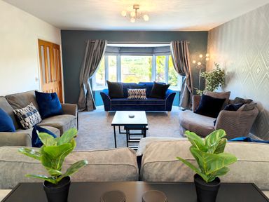 A living room with sofas cushions plants and a window at Sanderson House in Cleator Moor