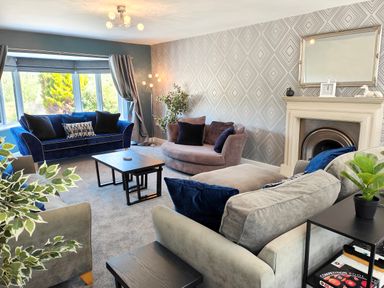 A living room with sofas table fireplace and plants at Sanderson House in Cleator Moor