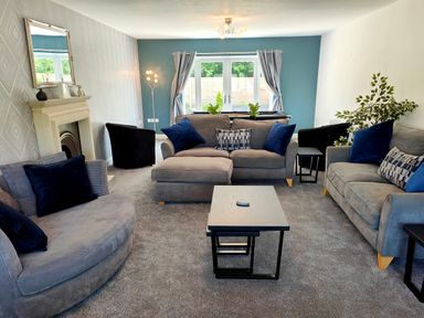 A living room with sofas cushions coffee tables and a fireplace at Sanderson House in Cleator Moor