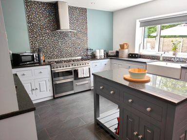 A kitchen with a large stove microwave island and window at Sanderson House in Cleator Moor