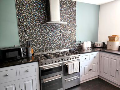 A kitchen with a gas stove oven microwave knife block toaster kettle and cabinets at Sanderson House in Cleator Moor