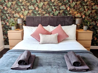 A bedroom with a bed with pillows towels and bedside tables with lamps and plants at Sanderson House in Cleator Moor