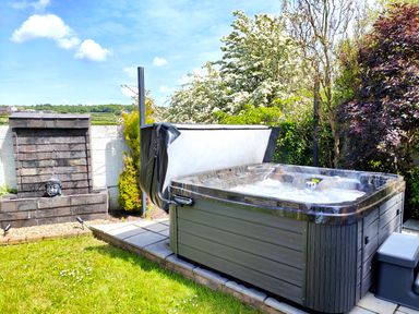 An outdoor area with a bubbling hot tub near a stone water feature and greenery at Sanderson House in Cleator Moor