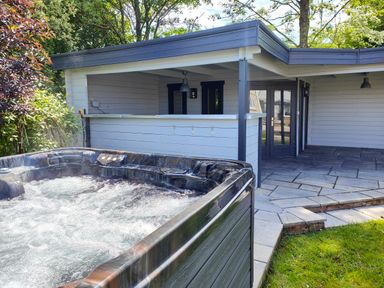 An outdoor hot tub next to a covered patio with tiled flooring at Sanderson House in Cleator Moor