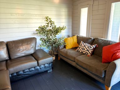 A corner living room with two gray sofas a potted plant and colorful cushions at Sanderson House in Cleator Moor