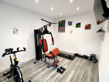 A gym room with exercise bike multigym weights and a wall mounted tv at Sanderson House in Cleator Moor