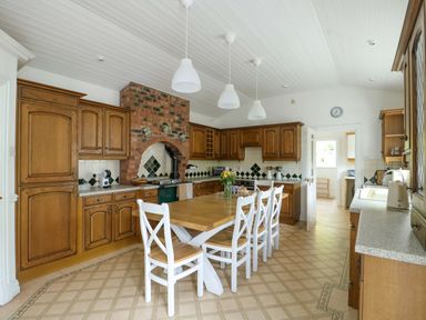 A kitchen with wooden cabinets and a large table at Bwthyn Clai in Llangefni