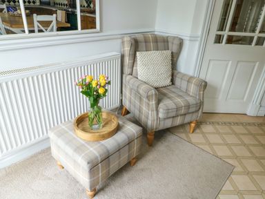 A living room with an armchair and ottoman in Bwthyn Clai Llangefni