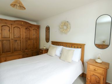 A bedroom with a bed, wardrobe, and nightstand at Bwthyn Clai in Llangefni