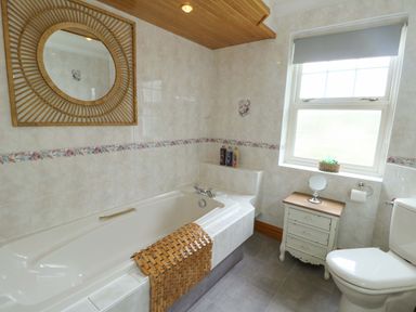 A bathroom with a bathtub, sink, and toilet at Bwthyn Clai Llangefni