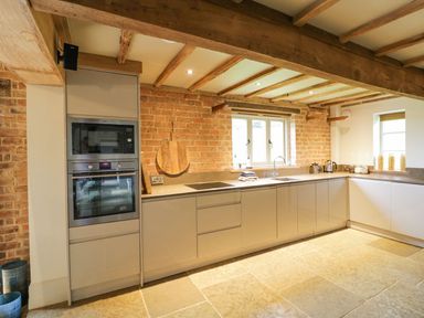 A kitchen with built in oven microwave cabinets and counter space with sink and window at Fairoaks Barns in Hollybush near Ledbury