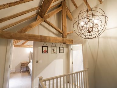 A hallway with wooden ceiling beams three framed pictures on the wall and a light fixture at Fairoaks Barns in Hollybush near Ledbury