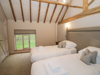 A bedroom with two single beds under a wooden beamed ceiling at Fairoaks Barns in Hollybush near Ledbury